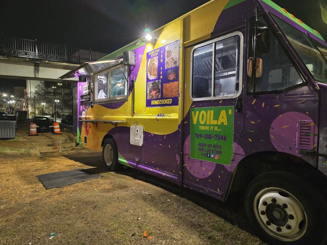 The purple, green and gold Voilá food truck lit up at night in Vicksburg, Mississippi